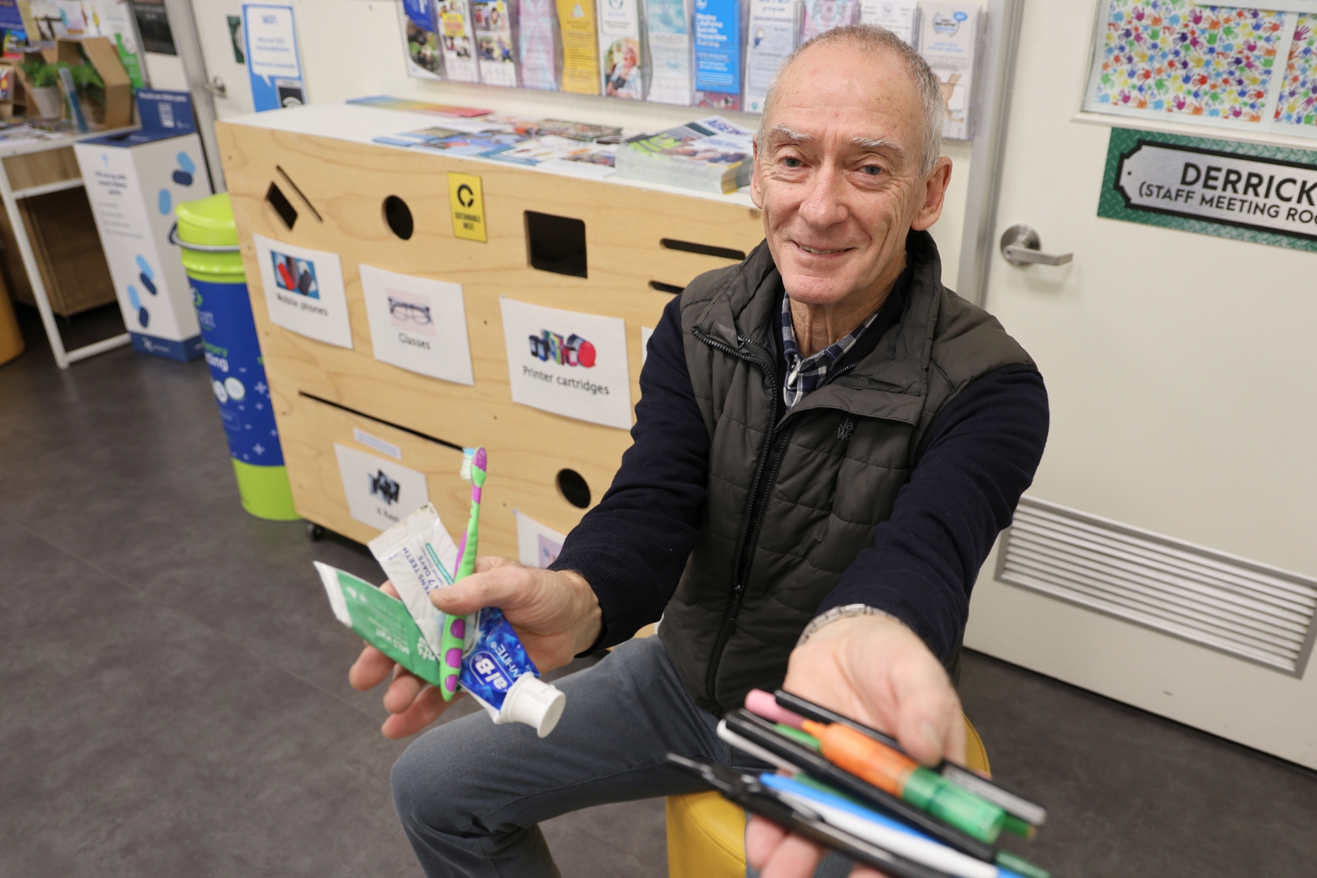 A man in front of the recycle station holds used pens