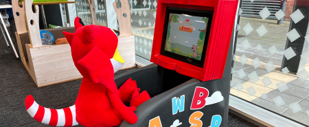 Lizzie, a stuffed lizard toy sitting in front of Storytime pod