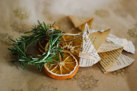 A sprig of rosemary, slices of orange and paper arranged in a decoration.